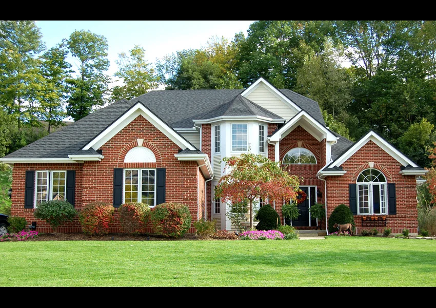 Dark colored shingle roof on a red brick house